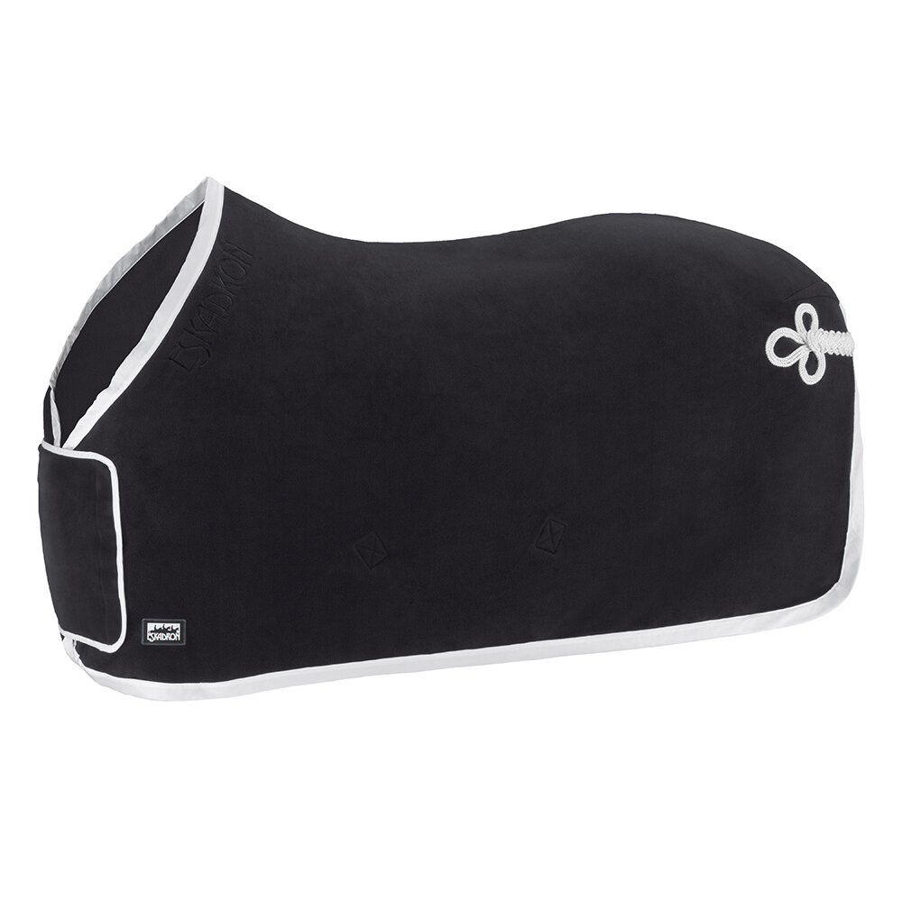 Ett svart fleecetäcke för häst, med en vit kant runt om. Täcket har ett flätat vitt svanssnöre och en broderad logotyp nära bogen.