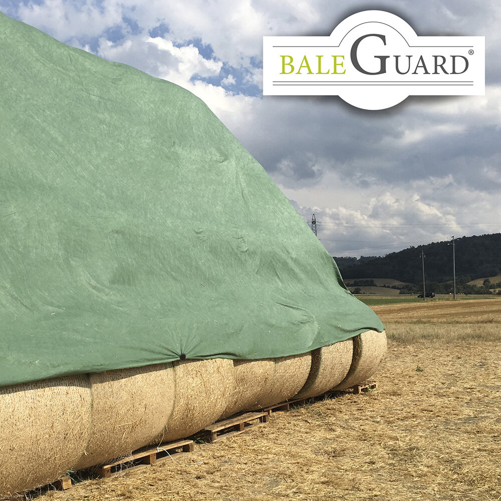 Rundbalar halm täckta av en stor grön presenning på ett fält under molnig himmel, med BaleGuard‑logotyp i hörnet.
